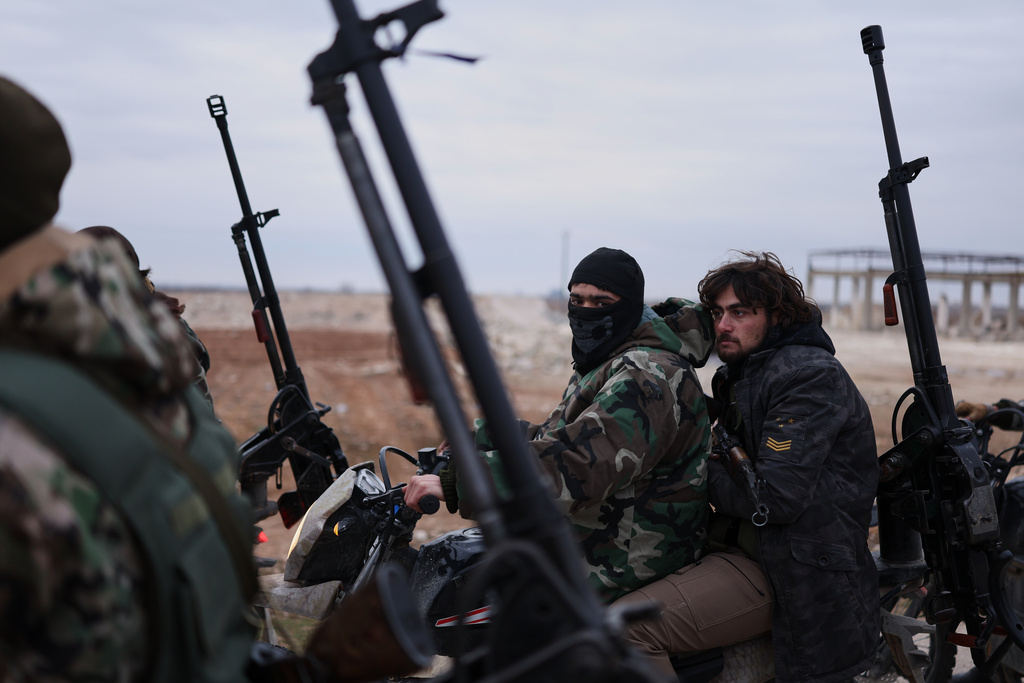 Syrian government soldiers carry machine guns as they ride motorcycles on a road leading to the town of Deir Hafer, Syria, Saturday, Jan. 17, 2026. (AP Photo/Ghaith Alsayed)