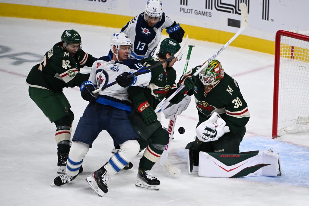 Minnesota Wild goaltender Jesper Wallstedt (30) stops a shot as defenseman Jared Spurgeon, left and defenseman Daemon Hunt, second from right, tries to clear Winnipeg Jets center Jonathan Toews (19) and center Gabriel Vilardi (13) from the goal during the second period of an NHL hockey game Thursday, Jan. 15, 2025, in St. Paul, Minn. (AP Photo/Craig Lassig)