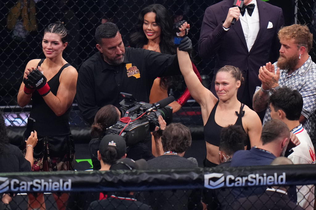 Ronda Rousey, of the United States, center, celebrates after defeating Gina Carano, of the United States, left, in their featherweight mixed martial arts fight Saturday, May 16, 2026, in Inglewood, Calif. (AP Photo/Jae C. Hong )