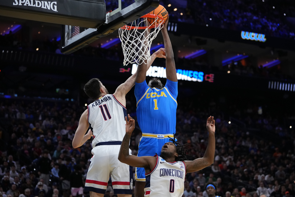 UCLA's Xavier Booker (1) goes up for a dunk against UConn's Alex Karaban (11) and Malachi Smith (0) during the first half in the second round of the NCAA college basketball tournament, Sunday, March 22, 2026, in Philadelphia. (AP Photo/Matt Slocum)