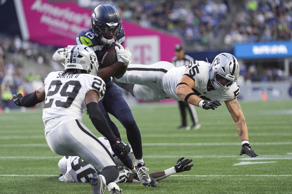 Seattle Seahawks wide receiver Tory Horton (15) goes to score against Las Vegas Raiders safety Chris Smith II (29) and linebacker Cody Lindenberg (55) during the first half of an NFL preseason football game Thursday, Aug. 7, 2025, in Seattle. (AP Photo/Lindsey Wasson)