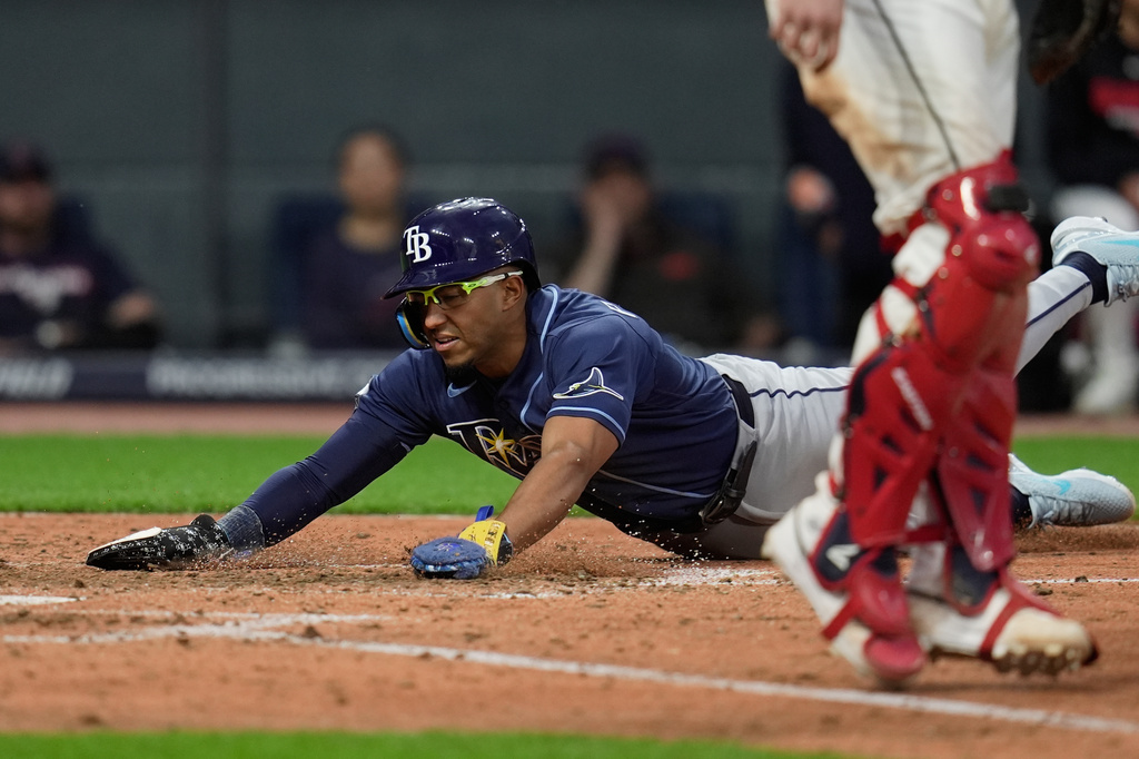Tampa Bay Rays' Richie Palacios, left, scores behind Cleveland Guardians catcher Austin Hedges in the eighth inning of a baseball game in Cleveland, Monday, April 27, 2026. (AP Photo/Sue Ogrocki)
