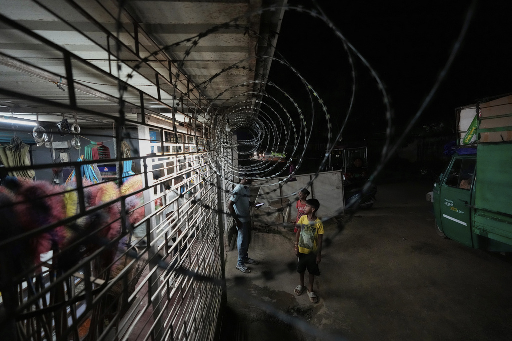 Children walk near barbwire installed on the perimeter of a shop to deter wild elephants near Amchang wildlife sanctuary on the outskirts of Guwahati, Saturday, Aug. 9, 2025. (AP Photo/Anupam Nath)
