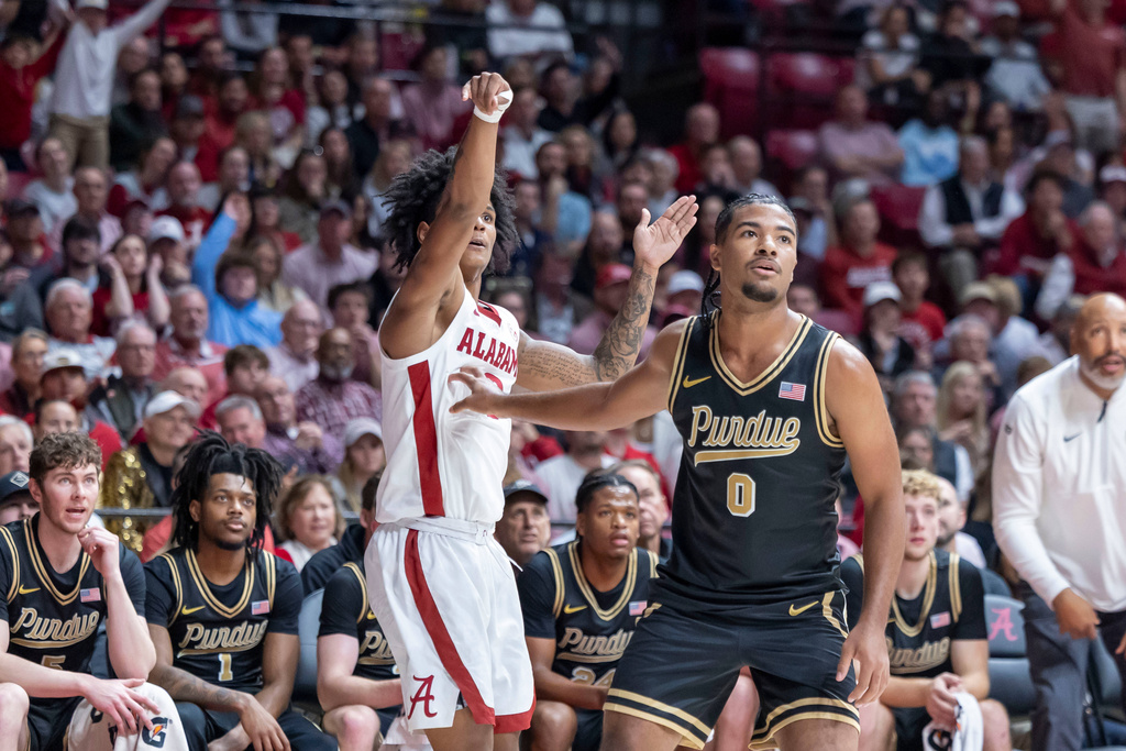Alabama guard Aden Holloway, left, shoots and hits a 3-point basket over Purdue guard C.J. Cox (0) during the first half of an NCAA college basketball game, Thursday, Nov. 13, 2025, in Tuscaloosa, Ala. (AP Photo/Vasha Hunt)