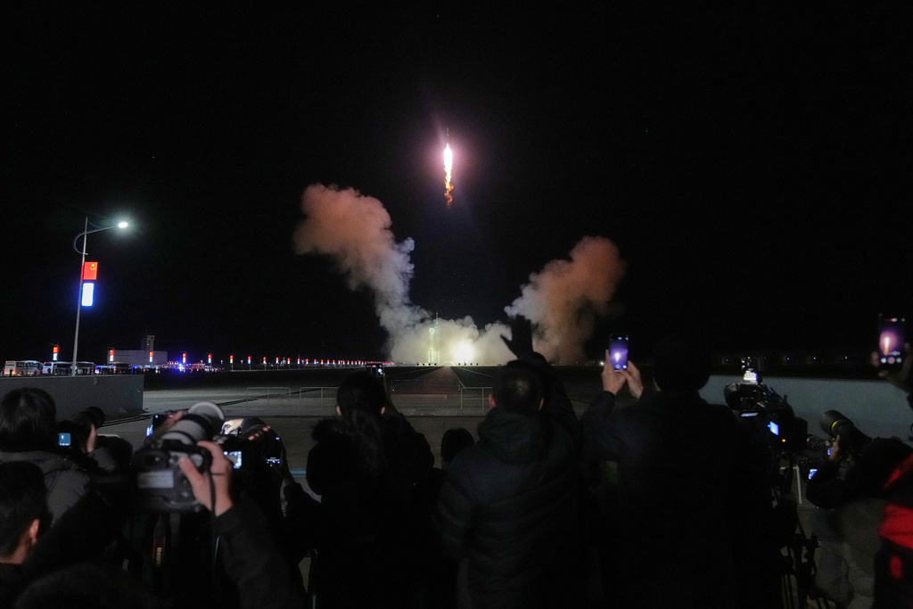 Journalists film China's Long March 2F rocket, carrying three astronauts for the Shenzhou 21 manned space mission, lifts off for a space station, at the Jiuquan Satellite Launch Center in Jiuquan, northwestern China, Friday, Oct. 31, 2025. (AP Photo/Andy Wong)
