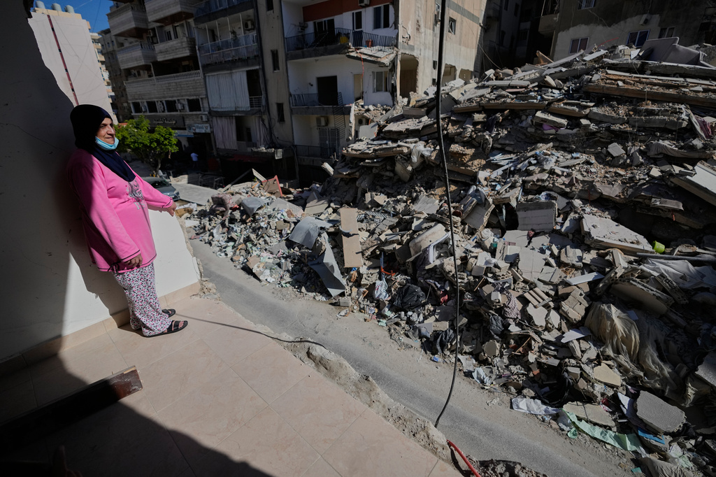 Em Ali Khodor, 75, looks through her damaged apartment into a destroyed building that was hit few weeks ago by an Israeli airstrikeafter she returns to the house, in the southern port city of Tyre, Lebanon, Thursday, April 30, 2026. (AP Photo/Hussein Malla)